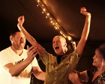 Teenage girl with arms raised in happiness after being baptised by full immersion